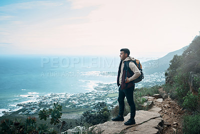 Buy stock photo Shot of a young man looking at the view from a cliff while out on a hike