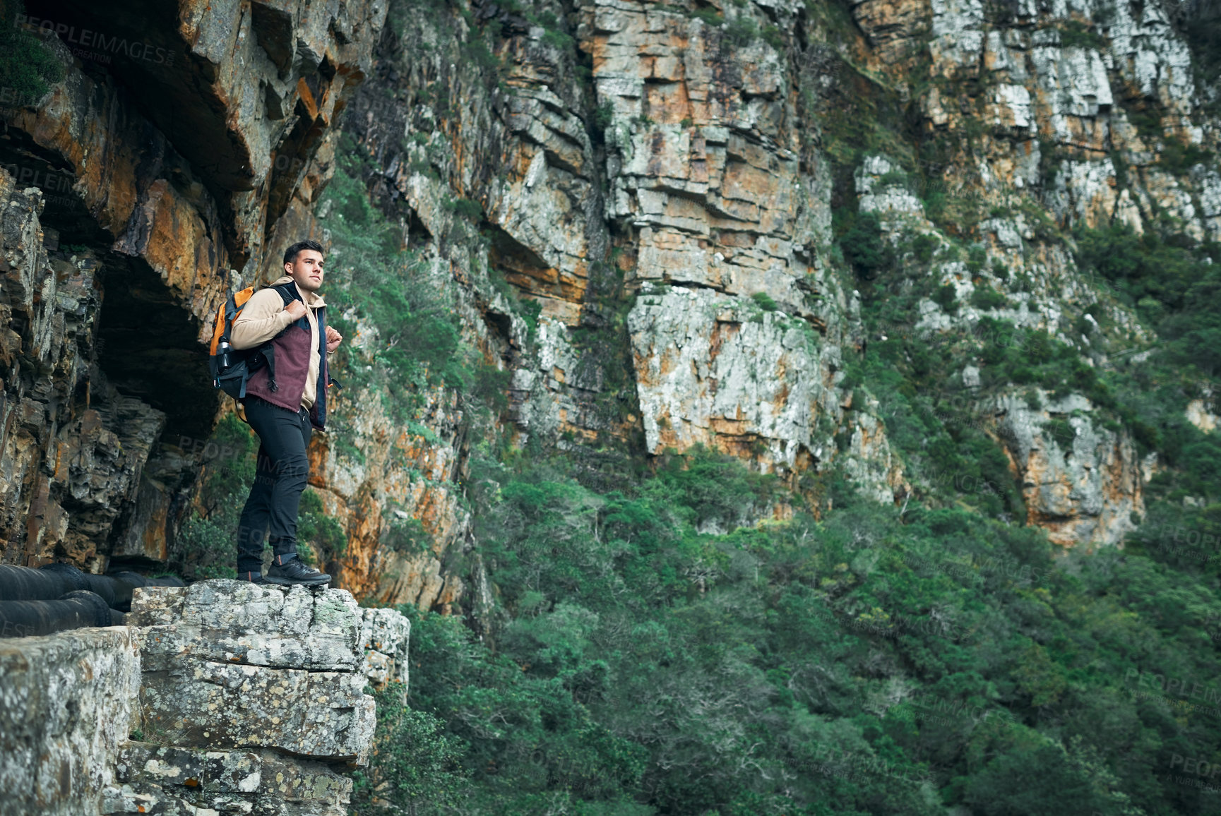 Buy stock photo Shot of a young man standing on a cliff while out on a hike