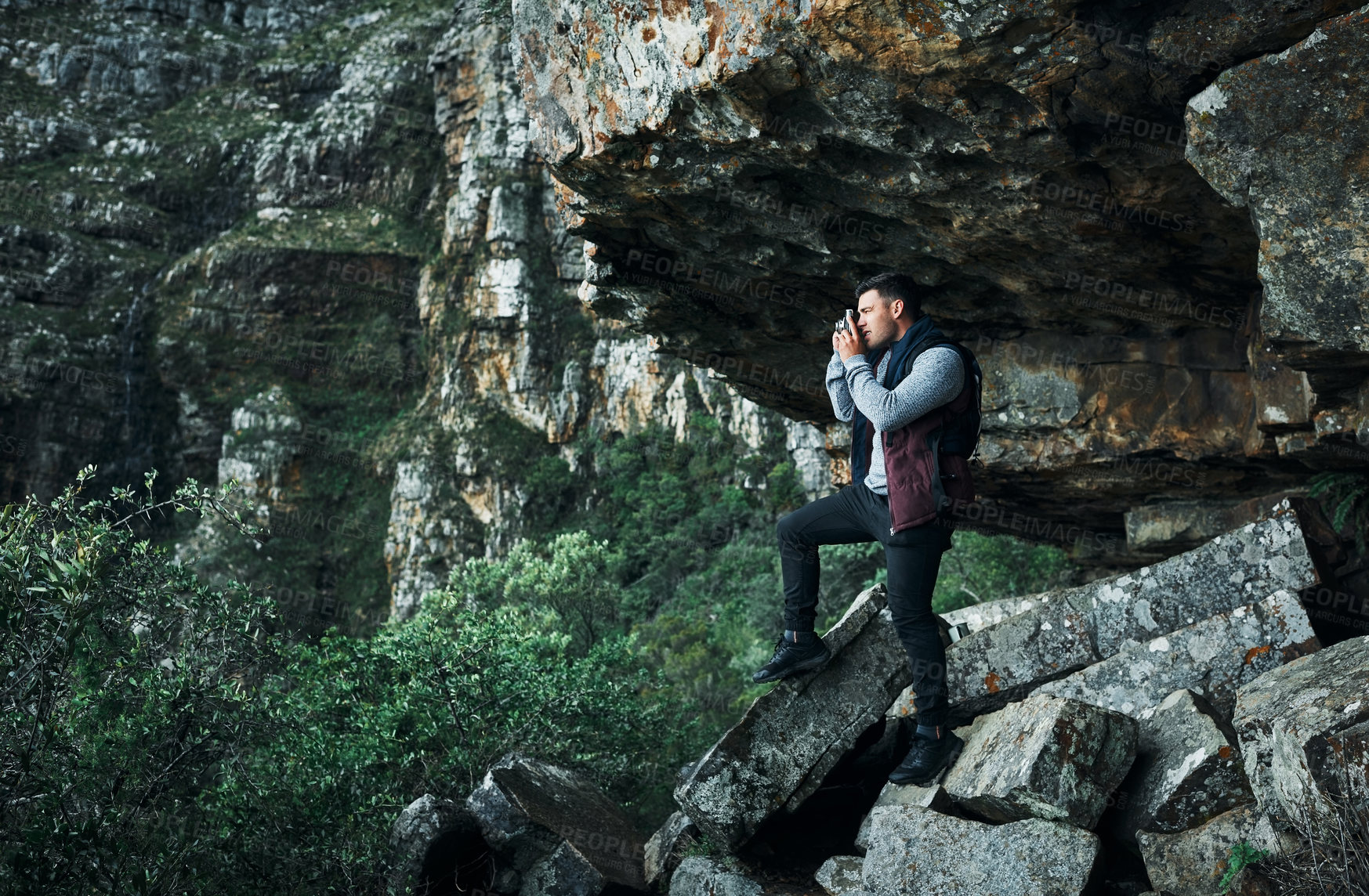 Buy stock photo Shot of a young man taking photos while out on a hike