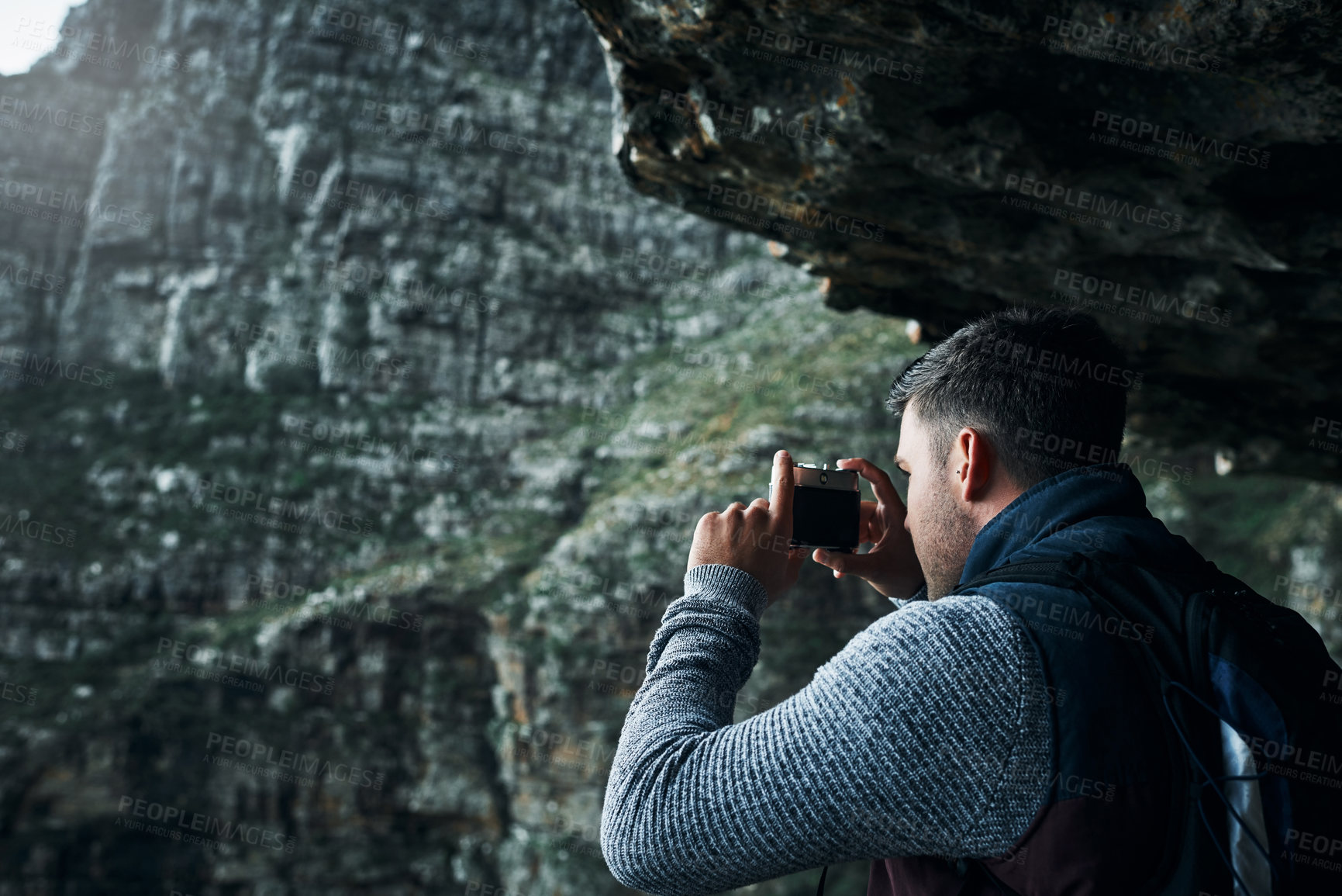 Buy stock photo Shot of a young man taking photos while out on a hike