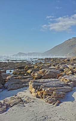 Buy stock photo Copyspace at sea with a blue sky background and rocky coast in Camps Bay, Cape Town in South Africa. Boulders at a beach shore with Table Mountain in the horizon on a summer day
