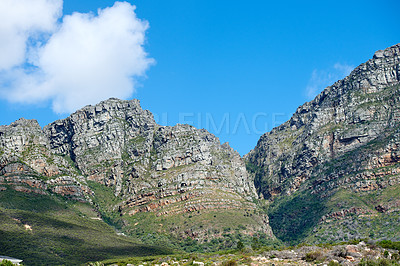 Buy stock photo Scenic landscape of mountains in Western Cape, South Africa against a cloudy blue sky background with copyspace. Scenic of plants and shrubs growing on a rocky hill and cliff in a natural environment