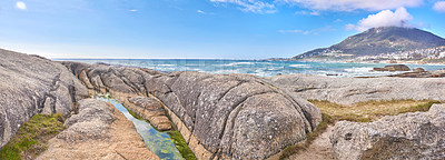 Buy stock photo Rocky coastline with the ocean and mountains in the background. Stunning nature landscape or seascape of rocks. Boulders or big natural stones in the sea with beautiful rough textures and copy space