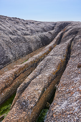 Buy stock photo Closeup of rough sea rock with deep cracks, crevices from ocean water erosion, global warming or climate change on beach. Texture detail of sedimentary rock acting as wave breaker on coastal seaside