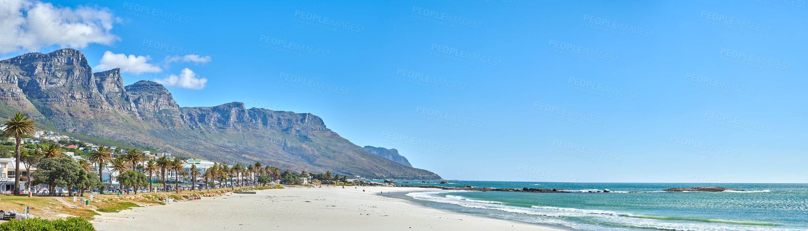 Buy stock photo Quiet and calm beach and ocean with sandy shore and palm trees. Scenic seascape of the Twelve Apostles mountain under a blue sky in Cape Town. A beautiful holiday destination for travel and tourism