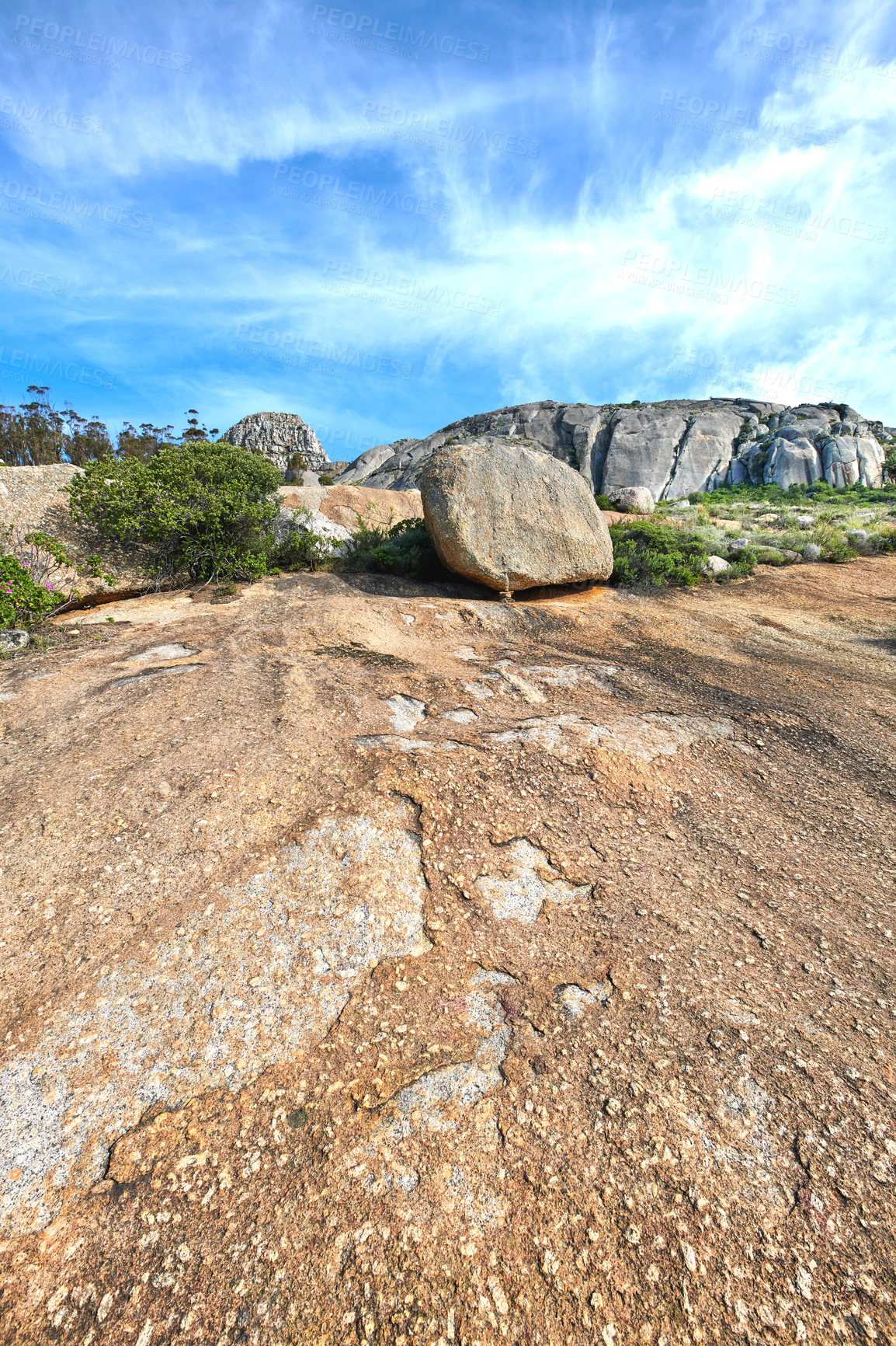 Buy stock photo Closeup of large rocks or boulders and shrubs near the mountains with a cloudy blue sky copyspace. Big stone structures on Table mountain. Famous tourist attraction and hiking trail in Cape Town