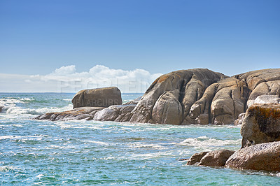 Buy stock photo Copy space at sea with a cloudy blue sky background and rocky coast in Camps Bay, Cape Town, South Africa. Boulders at a beach shore across a majestic ocean. Scenic landscape for a summer holiday