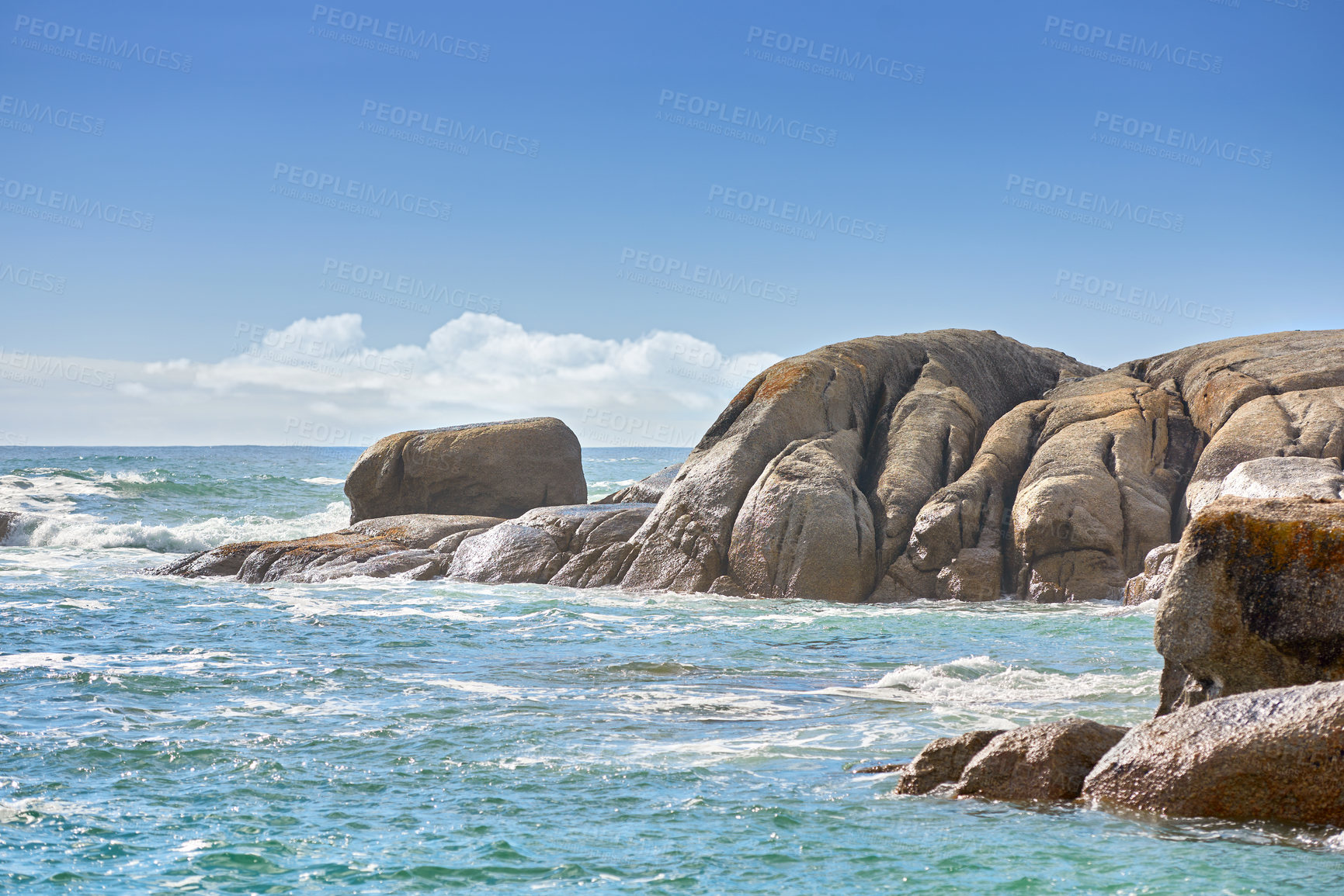 Buy stock photo Copy space at sea with a cloudy blue sky background and rocky coast in Camps Bay, Cape Town, South Africa. Boulders at a beach shore across a majestic ocean. Scenic landscape for a summer holiday