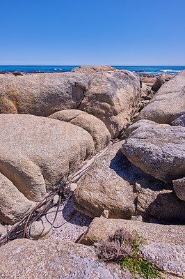 Buy stock photo Boulders at a beach shore with the majestic ocean horizon.
Copyspace at sea with blue sky background and rocky coast in Camps Bay Cape Town, South Africa with scenic landscape for a summer holiday
