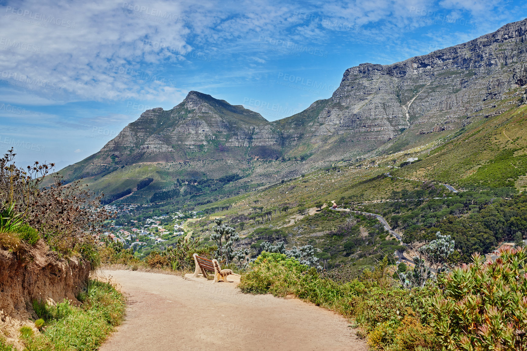 Buy stock photo Beautiful hiking trail on the mountains with a blue cloudy sky background. A zen, nature landscape with a bench overlooking green lush hills and roads for traveling on Table Mountain, South Africa