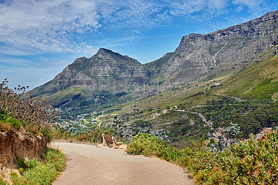 Buy stock photo Beautiful hiking trail on the mountains with a blue cloudy sky background. A zen, nature landscape with a bench overlooking green lush hills and roads for traveling on Table Mountain, South Africa