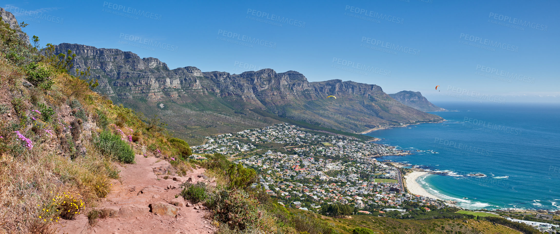 Buy stock photo Scenic hiking trail along Table Mountain with beautiful views of a coastal city against a blue sky background. Panoramic of a lush landscape by the sea around an iconic landmark to explore and travel