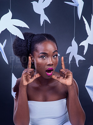 Buy stock photo Studio portrait of a beautiful young woman posing with paper birds against a black background