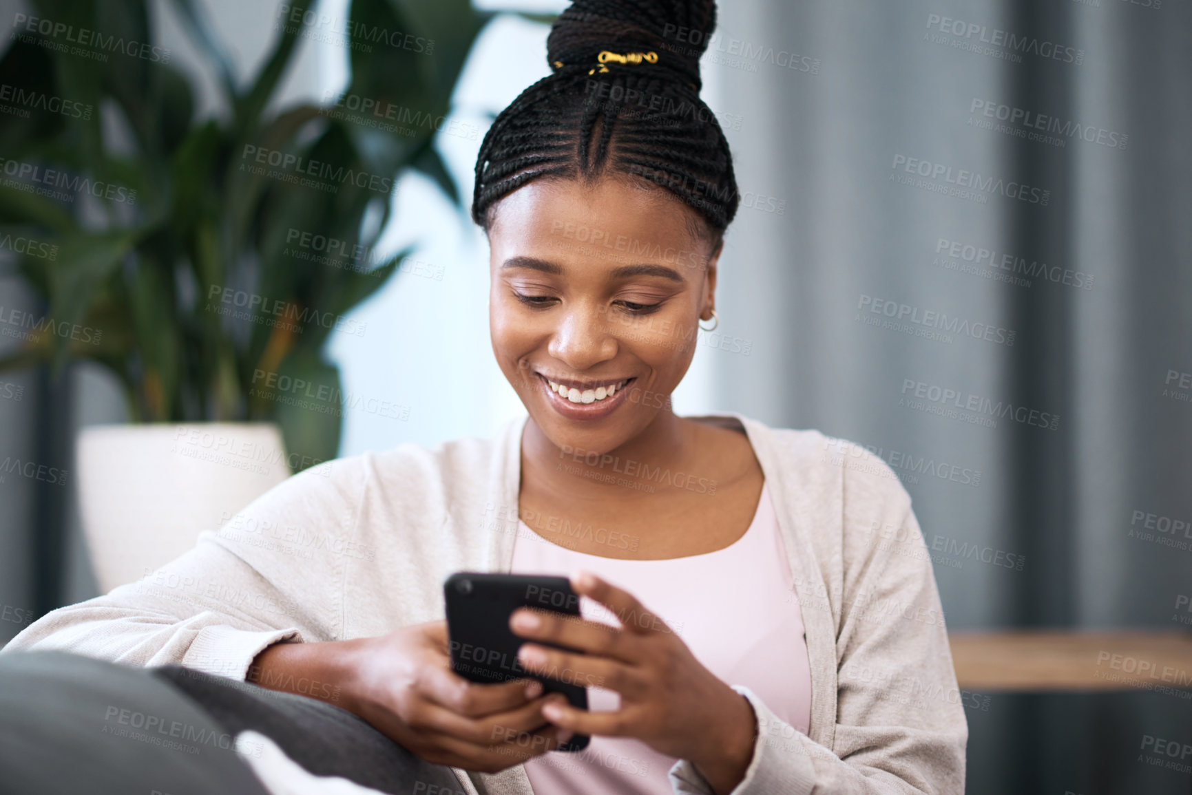 Buy stock photo Phone, relax and happy black woman in her living room networking on social media or the internet. Happiness, smile and African girl typing a text message on smartphone while relaxing on sofa at home.