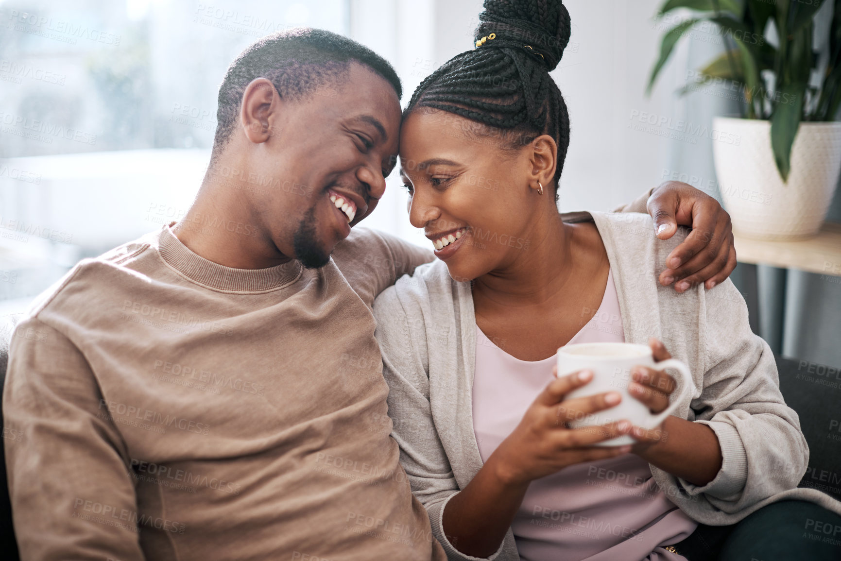 Buy stock photo Love, coffee and couple relax on a sofa, talking and embrace in the morning in their home. Black couple, man and woman enjoy tea on couch, bond and share sweet conversation in a living room together