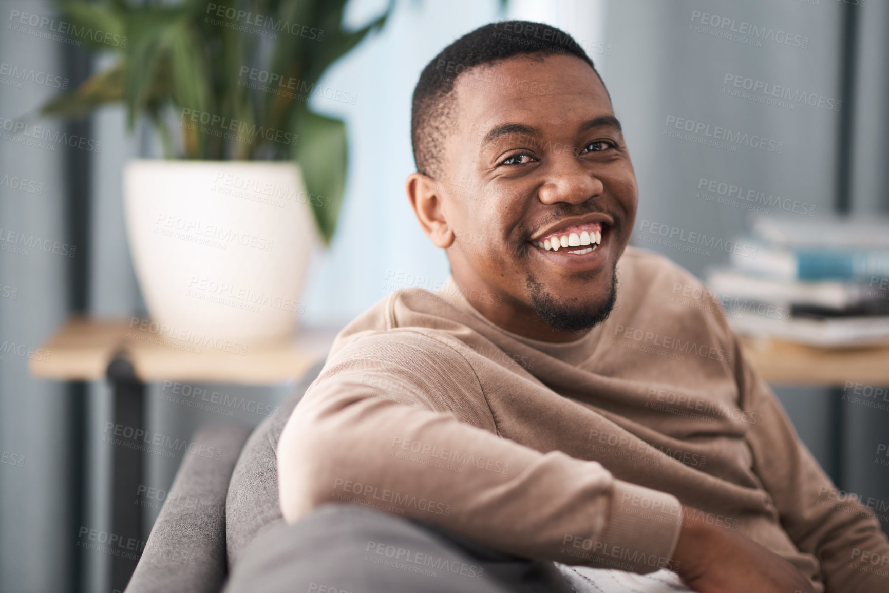 Buy stock photo Face, smile and portrait of a black man relax in a living room at a house on a holiday, break or weekend. Happiness, calm and young male sitting alone in a lounge in home or apartment relaxing
