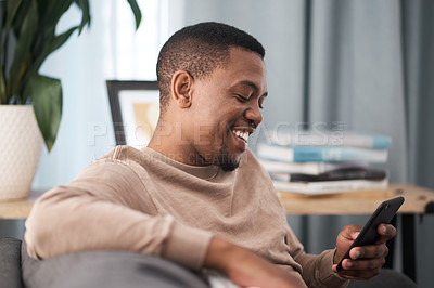 Buy stock photo Happy black man, smartphone and relax in home, living room sofa and typing online, social media notification and download web connection. Young african guy, mobile app game and 5g internet technology