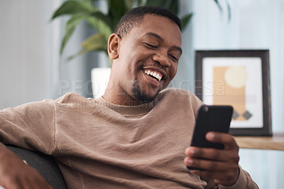 Buy stock photo Happy, phone and man in a living room texting, laughing and reading social media post in his home. Day off, black man and online chat on smartphone, text and funny message on dating website or app