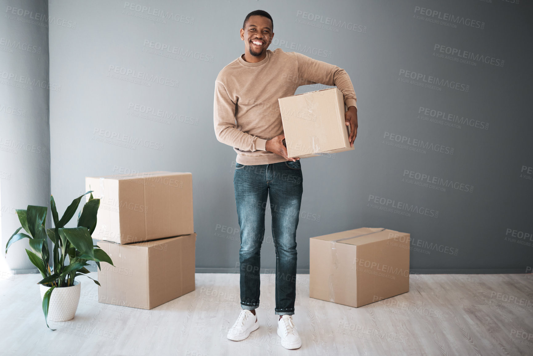 Buy stock photo Black man, moving and home portrait with box excited for real estate, property and new house. Boxes, happy and smile of home owner standing with cardboard boxes at gray wall advertising mockup.

