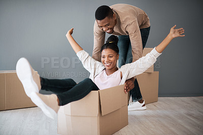 Buy stock photo Couple, box and moving into real estate, home and fun while unpacking, playing and bond in a living room. House, fun and man with woman on a floor playful, laughing and celebrating their dream home