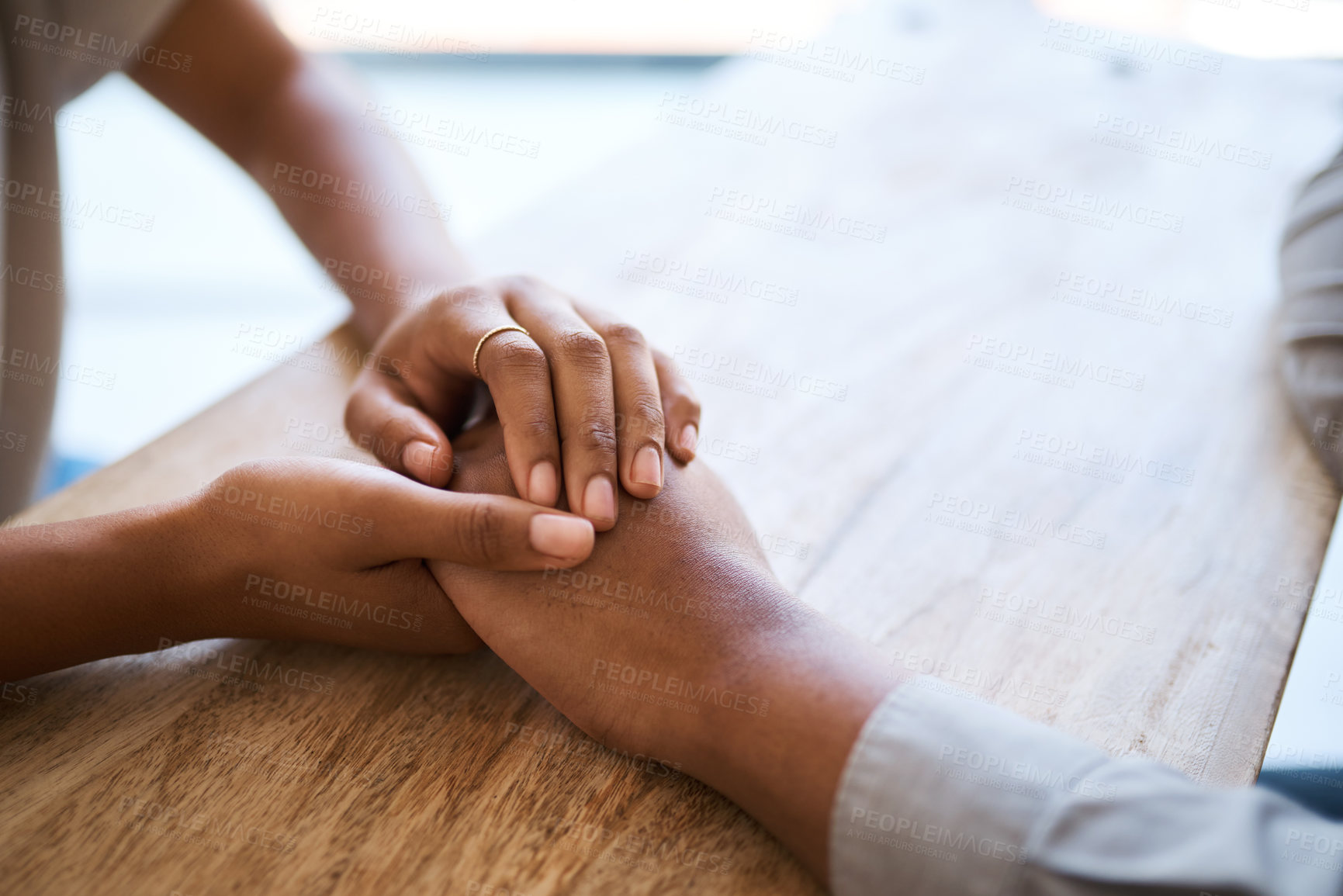 Buy stock photo Couple, holding hands and support on table in closeup for help, care and empathy in time of grief. Black couple, helping hand and love to forgive, consult or comfort together in home with kindness