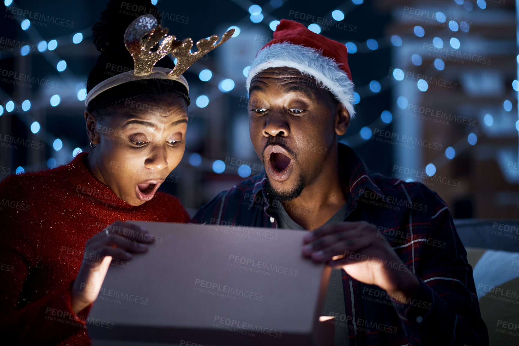 Buy stock photo Black couple, box and christmas gift open in surprise, wow and shock by magic light and looking excited. Night, couple and gift box fantasy, omg and amazed while sharing festive holiday in a home