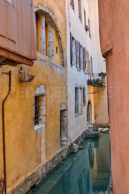 Buy stock photo Canal flowing between houses, roads and streets in the medieval part of the city of Annecy in France. Secluded and beautiful scenic view of a river running through a residential area in a small town