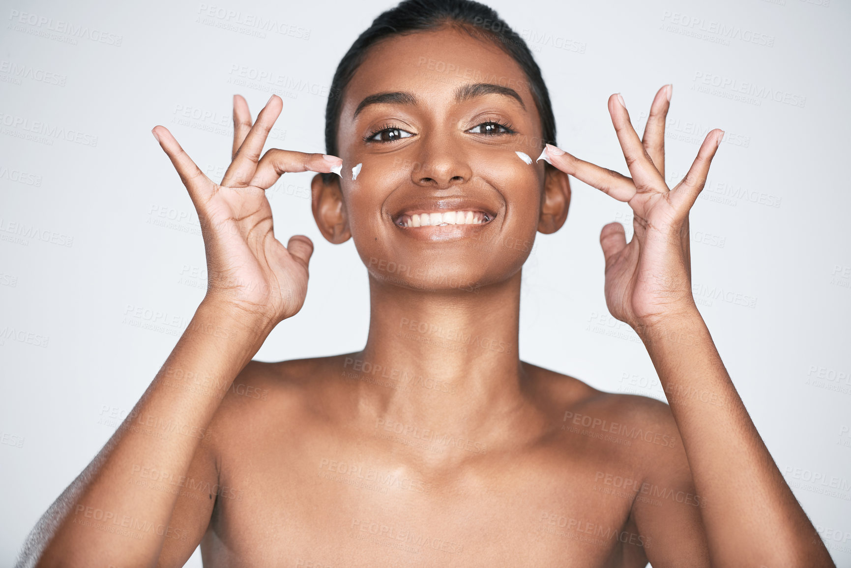 Buy stock photo Indian woman, beauty and skincare product with portrait, smile and excited for cosmetics or glow. Female person, happiness and dermatology for skin, moisturizer or facial treatment on gray background