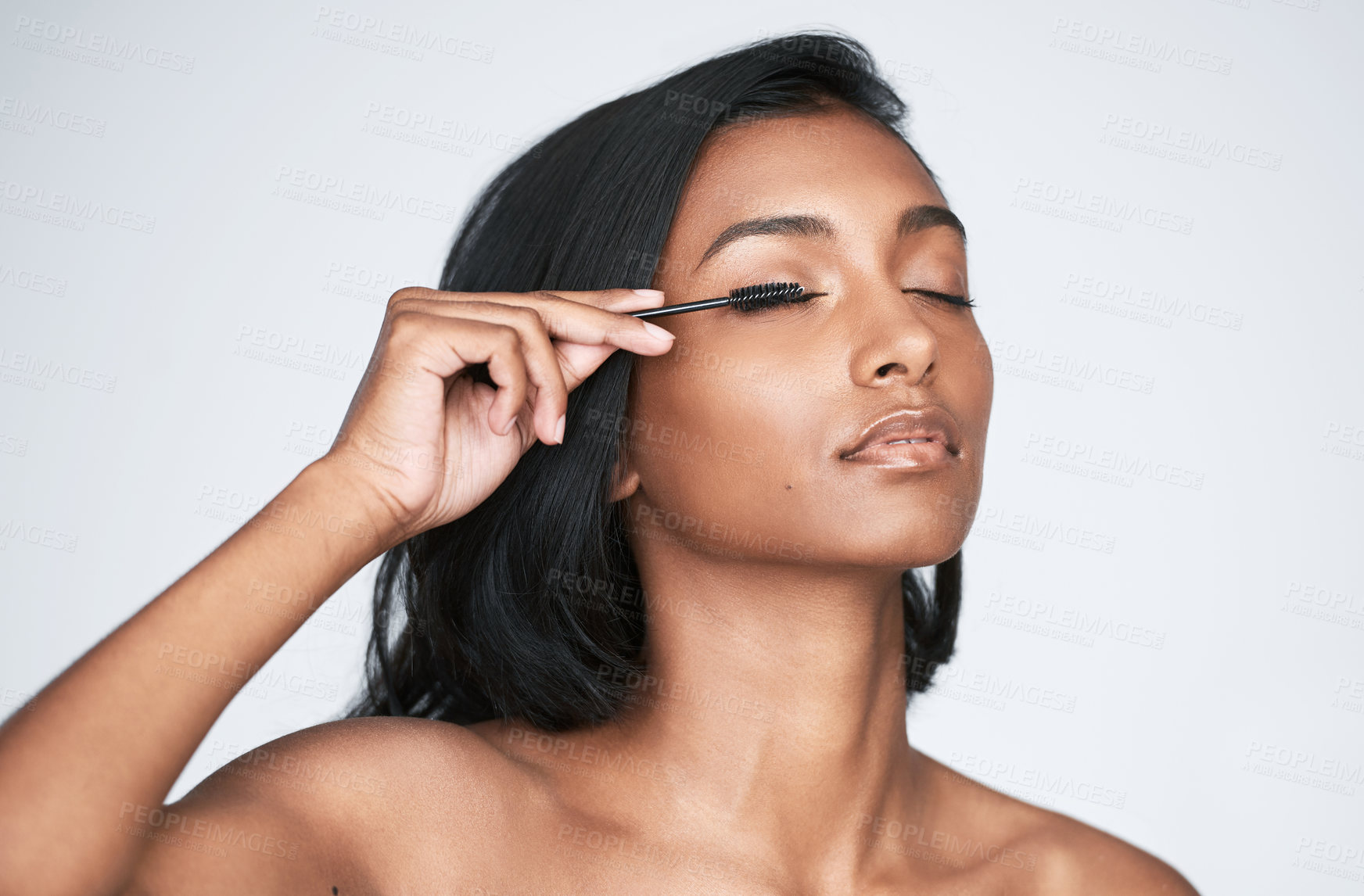 Buy stock photo Woman, eyelash and makeup with brush for beauty, volume or cosmetology on a white studio background. Young, female person or indian model applying lash curls for eye shade, hair filler or extension