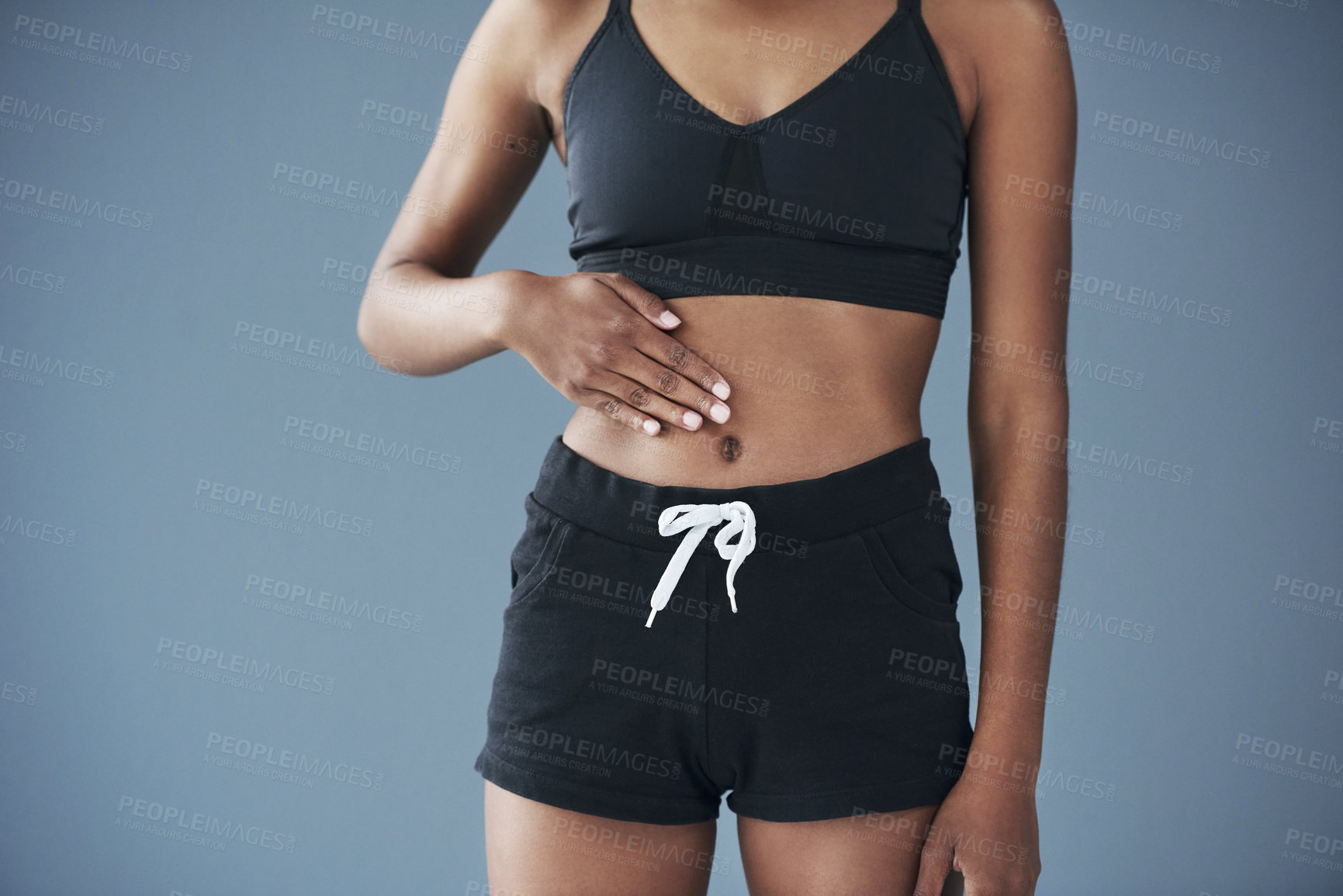Buy stock photo Closeup shot of a sporty young woman posing with her hand on her stomach