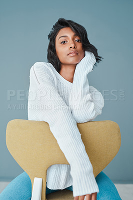 Buy stock photo Shot of a beautiful young woman sitting on a chair against a teal background