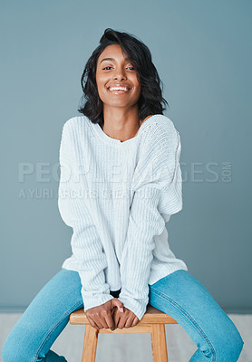 Buy stock photo Shot of a beautiful young woman sitting on a chair against a teal background