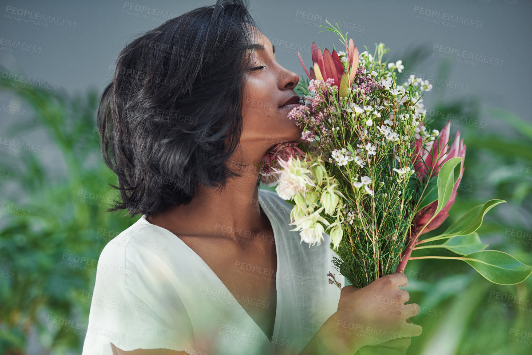 Buy stock photo Cropped shot of a beautiful young woman smelling a bouquet of flowers