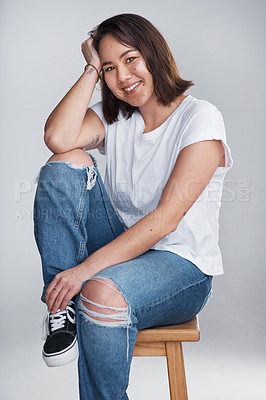Buy stock photo Cropped shot of a beautiful young woman sitting against a grey background