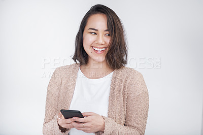 Buy stock photo Shot of a beautiful young woman using her cellphone while standing against a white background