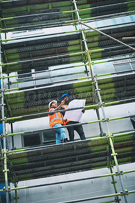 Buy stock photo Shot of a young man and woman going over building plans at a construction site