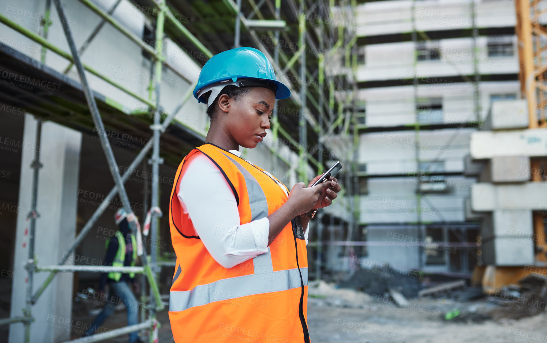 Buy stock photo Shot of a young woman using a smartphone while working at a construction site