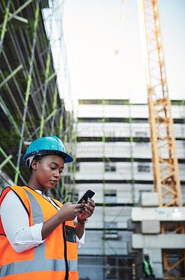 Buy stock photo Shot of a young woman using a smartphone while working at a construction site