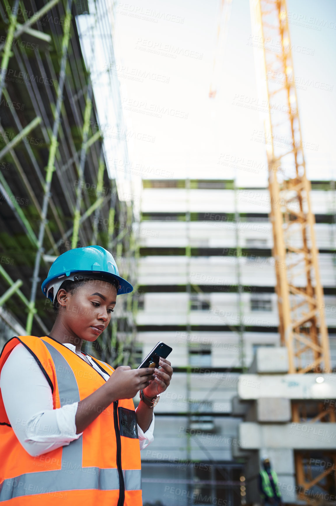 Buy stock photo Black woman, builder or civil engineer with phone at site for construction or maintenance. Young African, architect or safety worker on mobile smartphone for industrial communication in an urban city