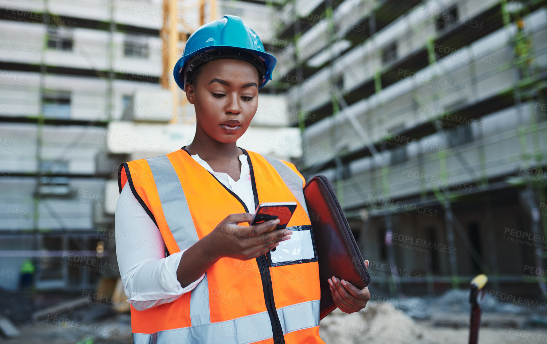 Buy stock photo Shot of a young woman using a smartphone while working at a construction site