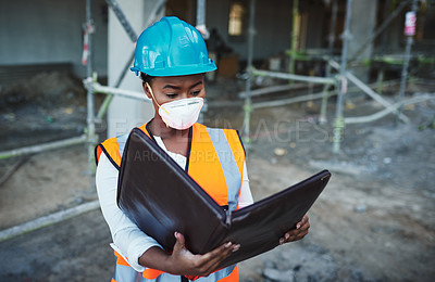 Buy stock photo Shot of a young woman going over building plans at a construction site