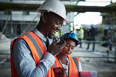 Buy stock photo Shot of a young man using a walkie talkie while working with his colleague at a construction site