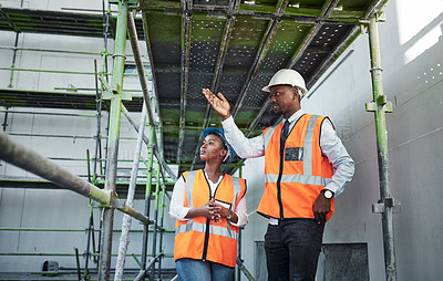 Buy stock photo Shot of a young man and woman having a discussion while working at a construction site