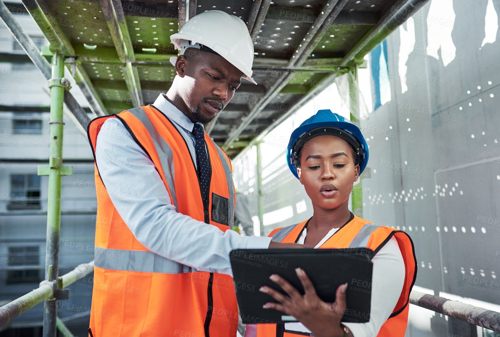 Buy stock photo Shot of a young man and woman using a digital tablet while working at a construction site