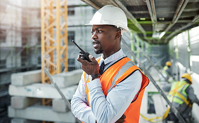 Buy stock photo Shot of a young man using a walkie talkie while working at a construction site