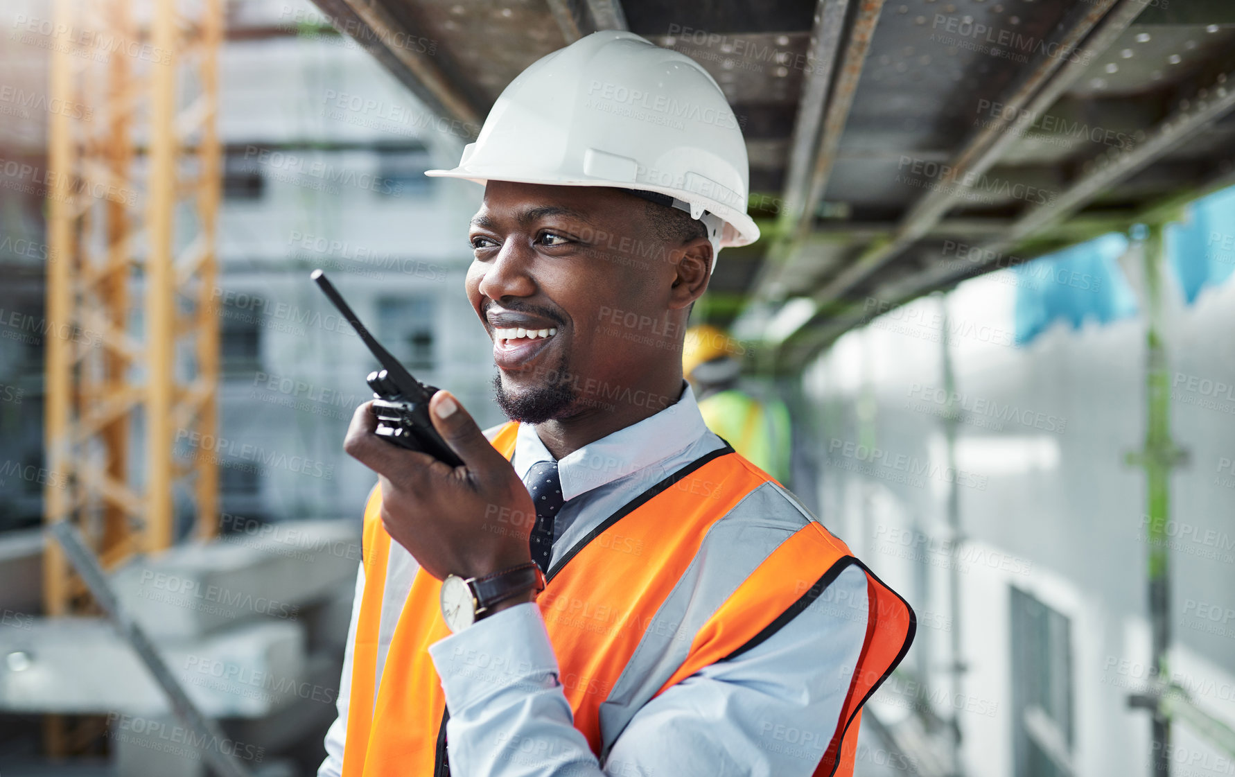 Buy stock photo Shot of a young man using a walkie talkie while working at a construction site