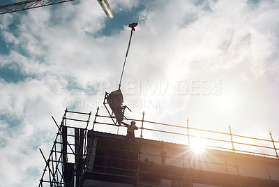 Buy stock photo Shot of a man lifting heavy machinery with a crane at a building site