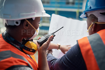 Buy stock photo Shot of a young man and woman going over building plans at a construction site