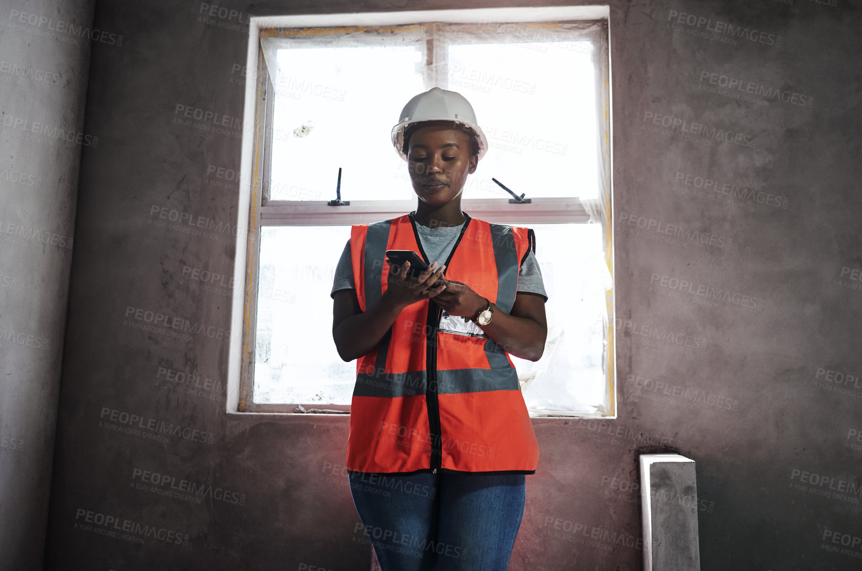 Buy stock photo Shot of a young woman using a smartphone while working at a construction site