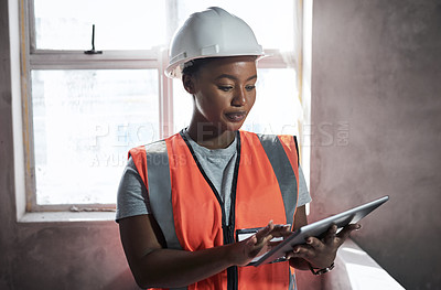 Buy stock photo Shot of a young woman using a digital tablet while working at a construction site